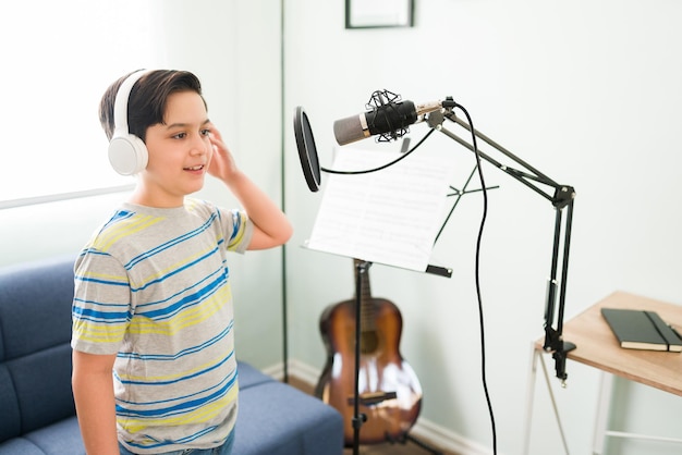 Practicing for my music lessons. Cute happy boy recording a song with a microphone for his singing classes