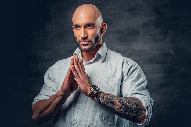 Free Photo praying shaved head male with tattoos on his arm.