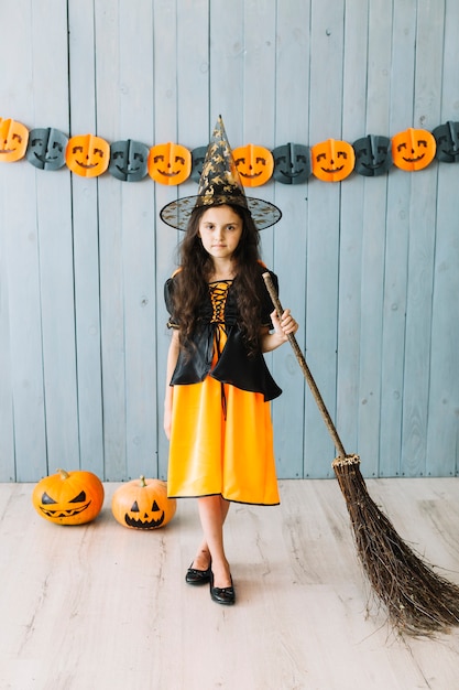 Free Photo pre-teen girl in pointy hat standing with broom