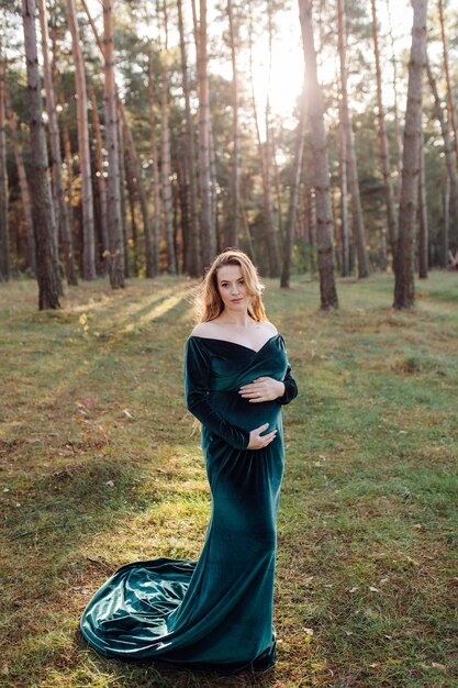 Pregnant happy young woman walking outdoors in forest