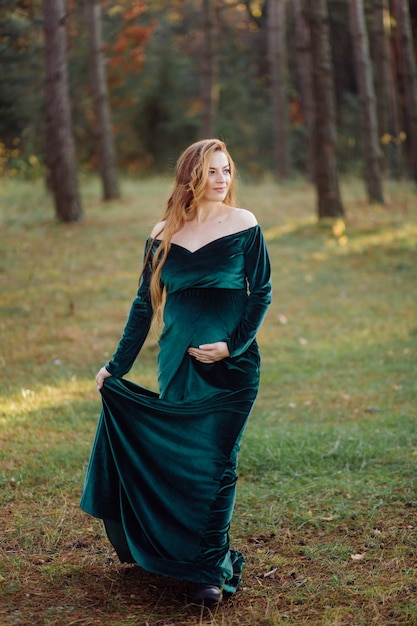 Free photo pregnant happy young woman walking outdoors in forest