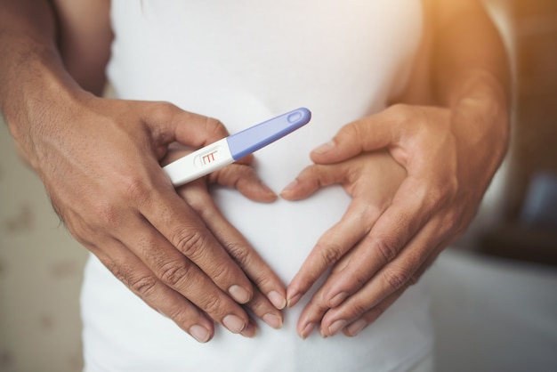 Pregnant Woman and Her Husband hand showing heart shape.