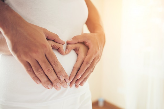 Free photo pregnant woman and her husband hand showing heart shape.