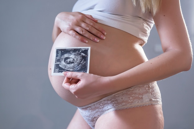 Pregnant woman holding photo of her future baby