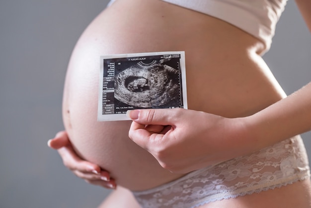 Free Photo pregnant woman holding an x-ray in front of her belly high