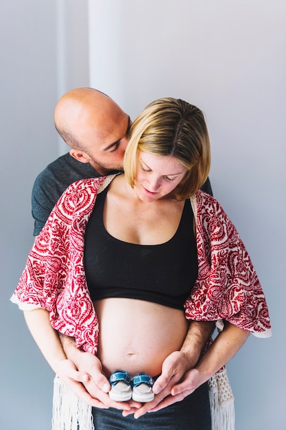 Free Photo pregnant woman and husband with baby shoes