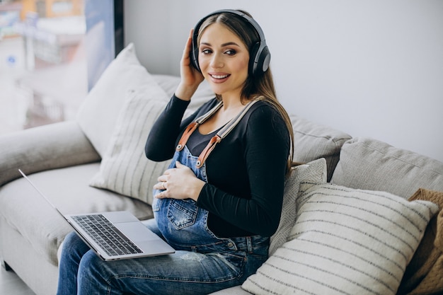 Pregnant woman listening to music in earphones and surfing the internet