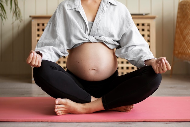 Free Photo pregnant woman practicing yoga at home