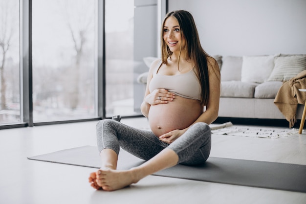 Free photo pregnant woman practicing yoga on mat at home