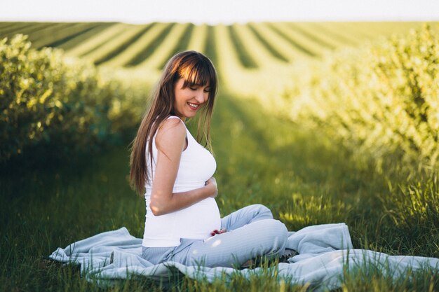 Pregnant woman practising yoga in field