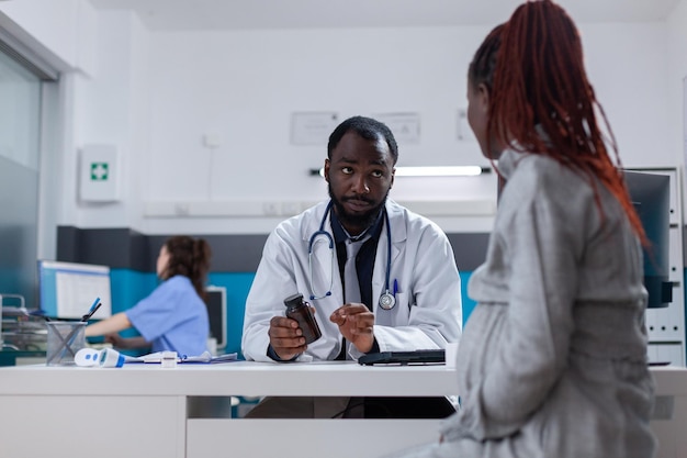 Pregnant woman receiving bottle of pills from specialist to cure disease. Healthcare physician giving prescription treatment and medicine to patient with pregnancy in medical office