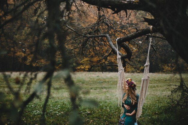 Free Photo pregnant woman rests outside on the rope swing hanging 