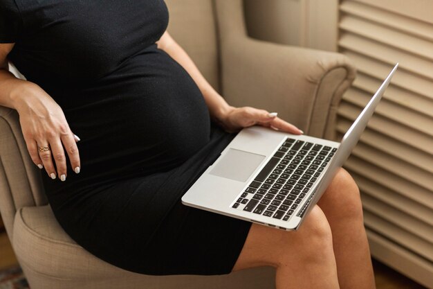 Pregnant woman sitting on a chair and working on laptop