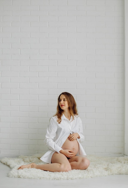 Pregnant woman in the studio In a white shirt