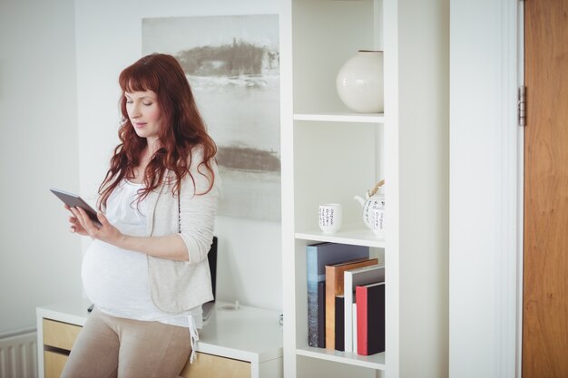 Pregnant woman using digital tablet in study room