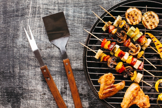 Preparation of grilled meat on barbecue grill over wooden background