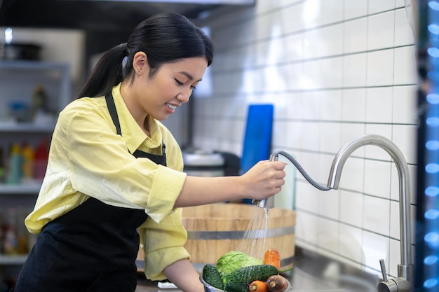 Preparation. Woman in the kitchen washing vegetables before cooking