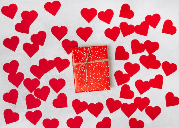 Present box between heap of paper decorative hearts