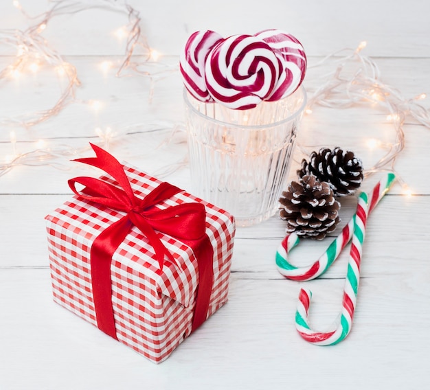 Present box near glass with lollipops, candy canes and fairy lights 