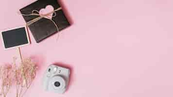 Free photo present box with ornament heart, camera, twig and tablet