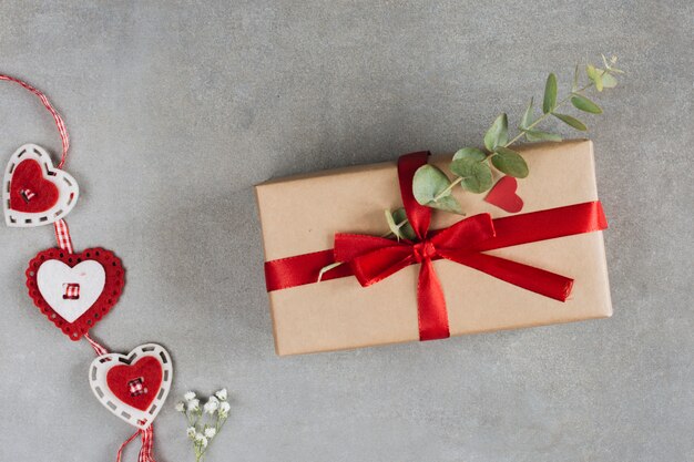 Present box with plant twig near ornament hearts 