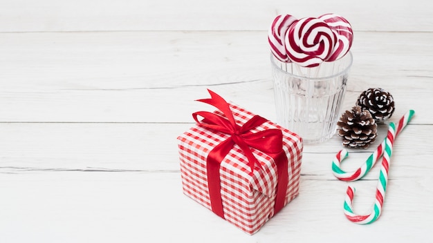 Free photo present box in wrap near glass with lollipops and candy canes