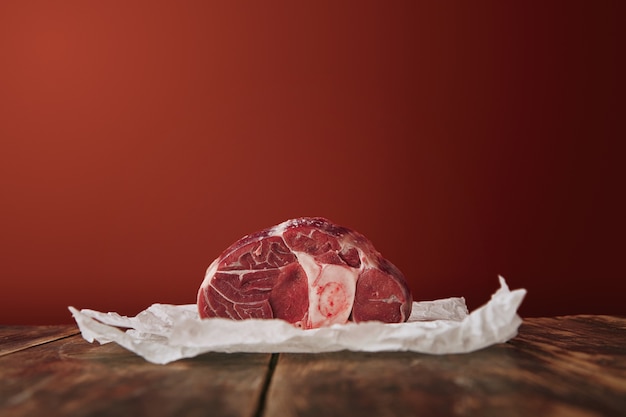 Free Photo presentation of raw angus leg steak on white craft paper wooden table red background