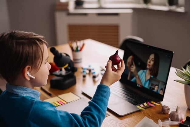 A Preteen boy uses a laptop to make a video call with his teacher