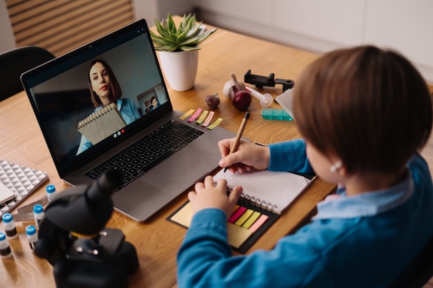 A Preteen boy uses a laptop to make a video call with his teacher