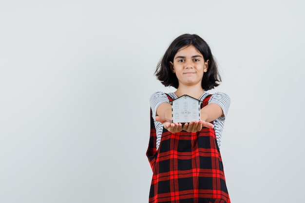 Free photo preteen girl showing model house in t-shirt, jumpsuit