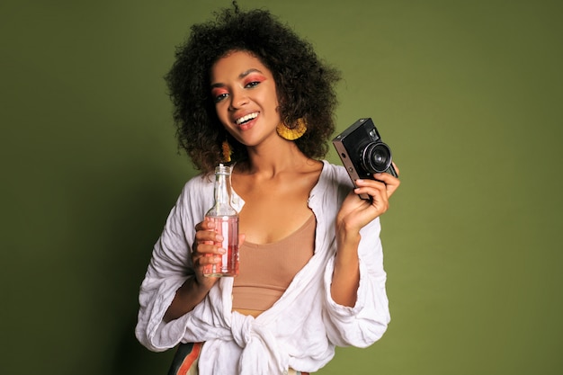 Free photo pretty african woman with afro hairstyle posing, drinking lemonade from straw. summer style. bright make up.