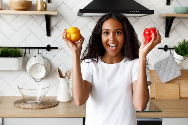 Pretty afro woman smiling holds two pepper