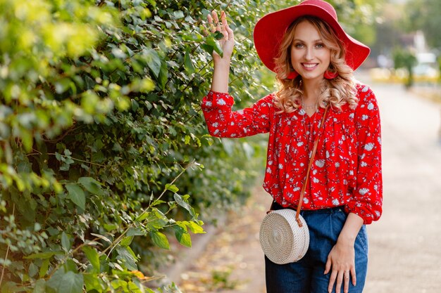 Pretty attractive stylish blond smiling woman in straw red hat and blouse summer fashion outfit