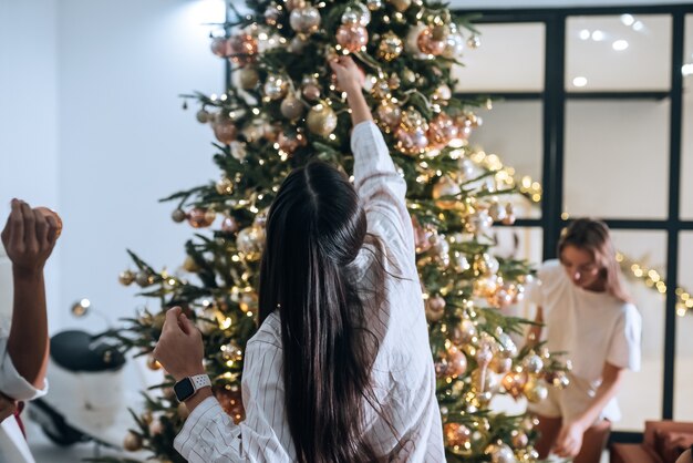 Pretty attractive women decorates the christmas tree with balls