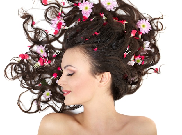 Free photo pretty beautiful girl lying with bright red flowers in her hair bright makeup isolated on white