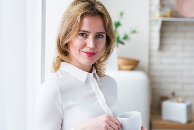 Free photo pretty blond business woman standing with coffee cup