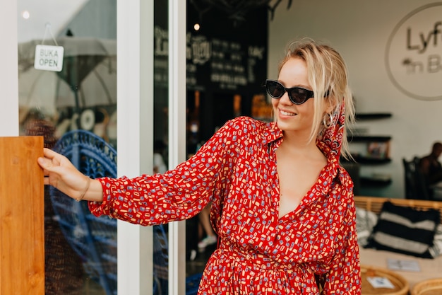 Free Photo pretty charming lady in summer bright dress and sunglasses going out from stylish cafeteria