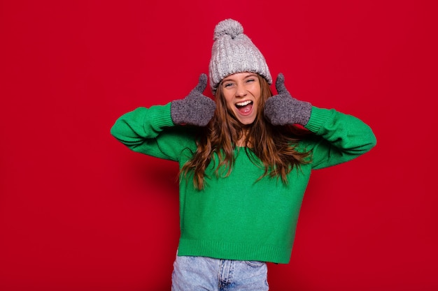 Free Photo pretty charming young woman on red wall in winter outfit