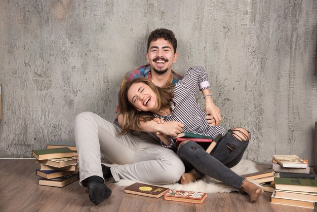 pretty couple sitting on the floor with a lot of books