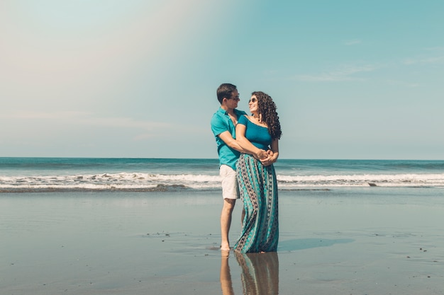 Pretty couple smiling and looking at each other on beach