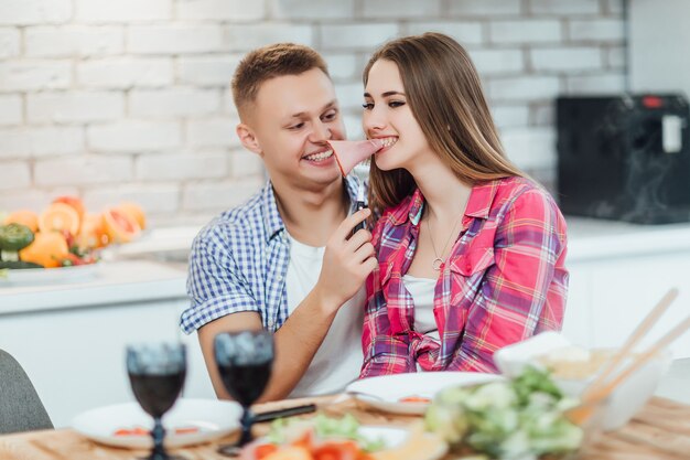 Pretty couple toasting ham at home kitchen. Romantic time.