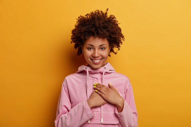 Pretty curly haired woman presses palms to heart