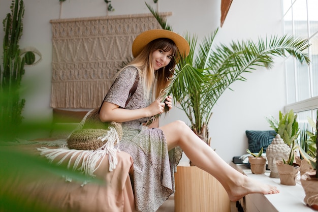 Free photo pretty female  sitting on bed in her boho apartment