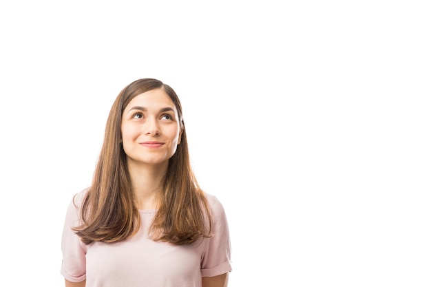 Free photo pretty female smiling while looking up at blank space over white background