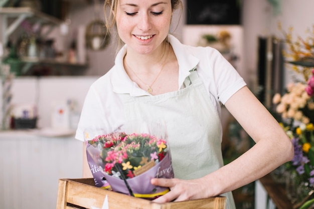 Free photo pretty florist carrying flowers in box