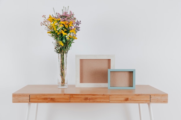 Free Photo pretty flowers near frames on table