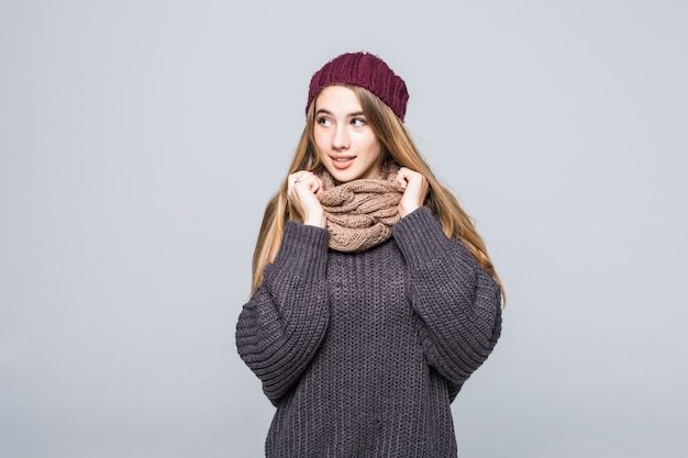 Free photo pretty girl in grey sweater and scarf is cold on gray