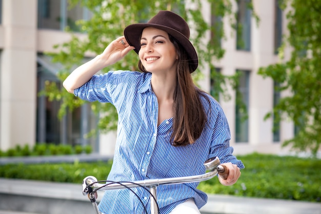 Pretty girl in hat riding a bicycle at street