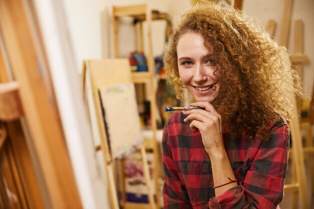 Pretty girl holds a brush near her chin and smiles