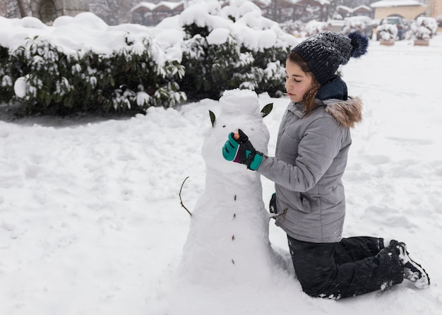 Free Photo pretty girl making snowman during winter season